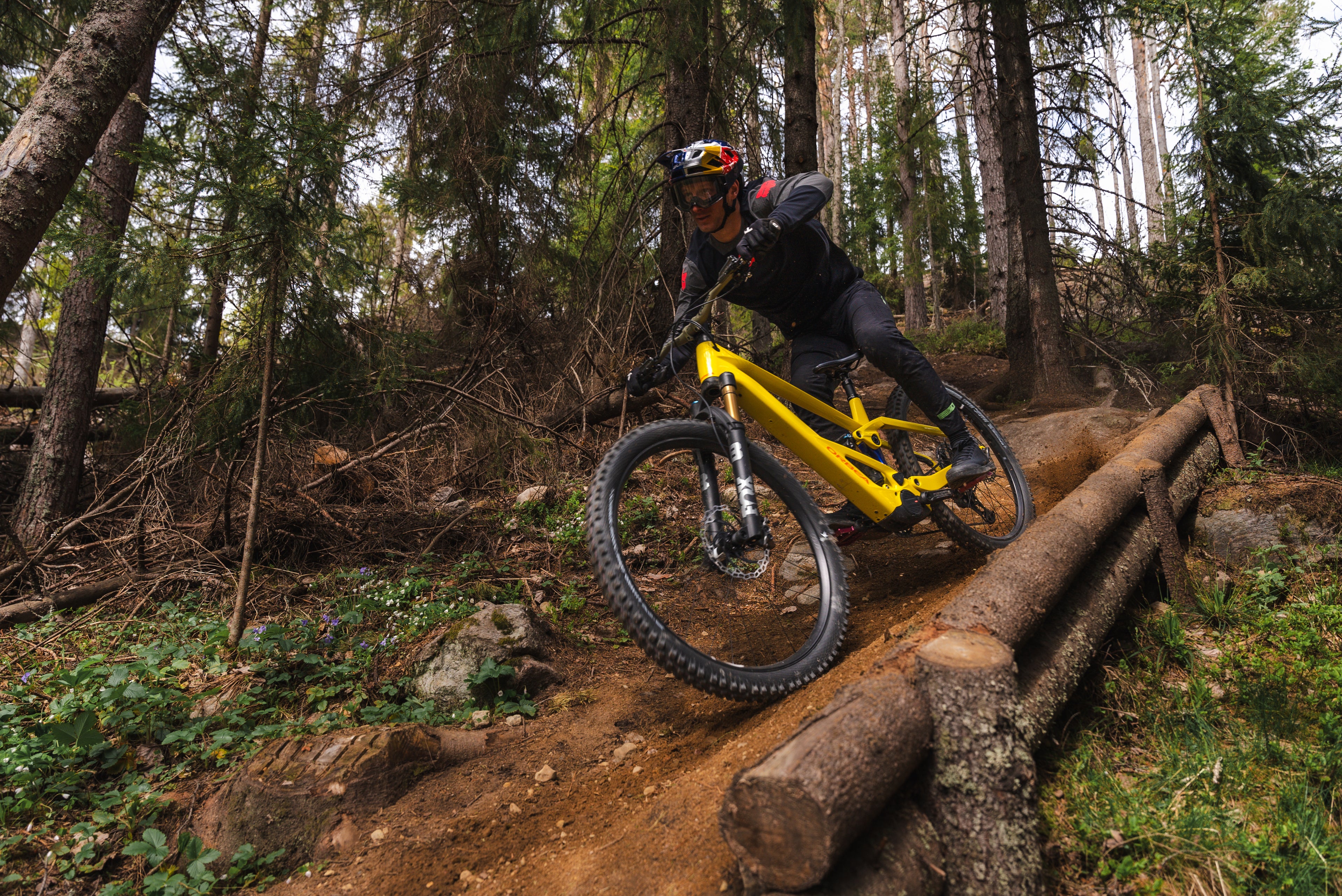 Red bull keppnishjólari brunar niður skógi vaxna fjallshlíð á gulu nýja Wild LT fulldempaða enduro rafmagnsfjallahjólinu.